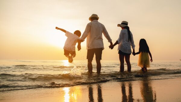 imagem de uma família formada por quatro pessoas em um pôr no sol na praia