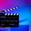 Imagem de uma claquete. Mão segurando claquete de produção de filme em um fundo colorido em um estúdio para filmagem ou gravação de filme.