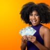 Mulher segurando notas de dinheiro brasileiras, sorrindo, em um fundo gradiente laranja.