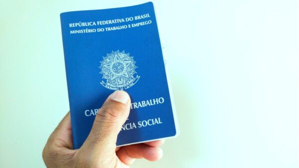 Mão segurando documento brasileiro de trabalho e previdência social (Carteira de Trabalho e Previdência Social).