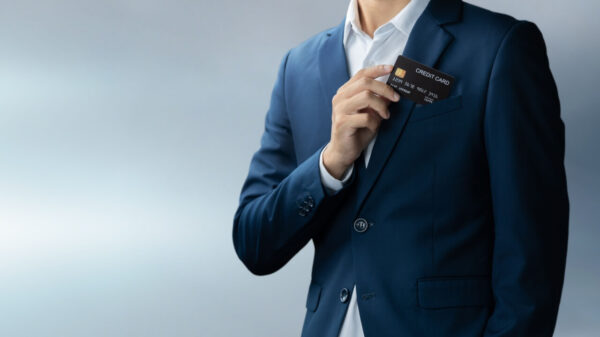 Homem de terno azul colocando ou retirando um cartão de crédito do bolso.