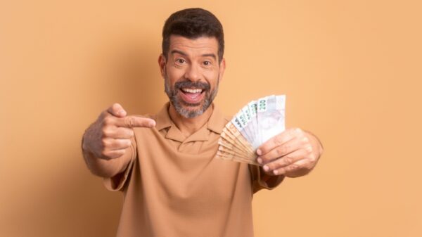 homem feliz segurando um leque de dinheiro em fundo laranja