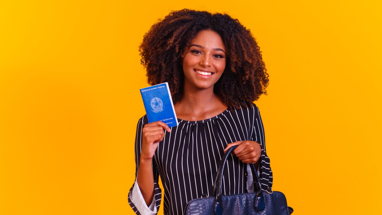 mulher segurando uma bolsa e uma carteira de trabalho em fundo amarelo