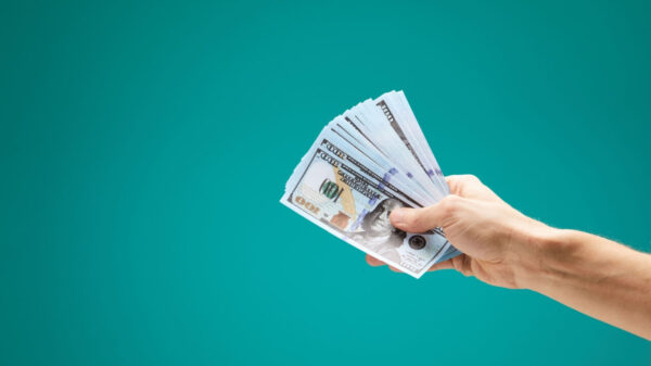 Mão masculina segurando notas de dinheiro isolada em um fundo verde. Conceito de grande lucro.