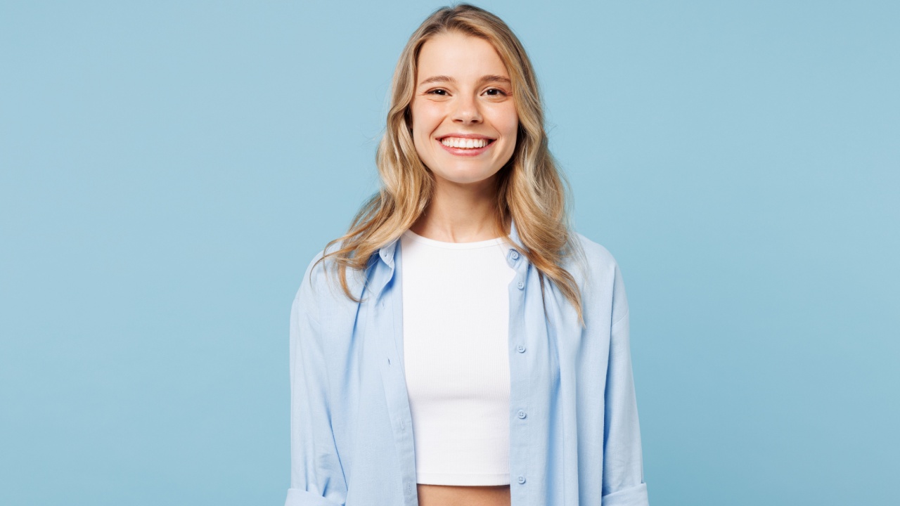 mulher sorrindo no centro da imagem em fundo azul