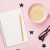 Xícara de café, óculos, lápis e caderno. Vista superior; fundo rosa. Conceito de planejamento.
