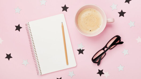 Xícara de café, óculos, lápis e caderno. Vista superior; fundo rosa. Conceito de planejamento.