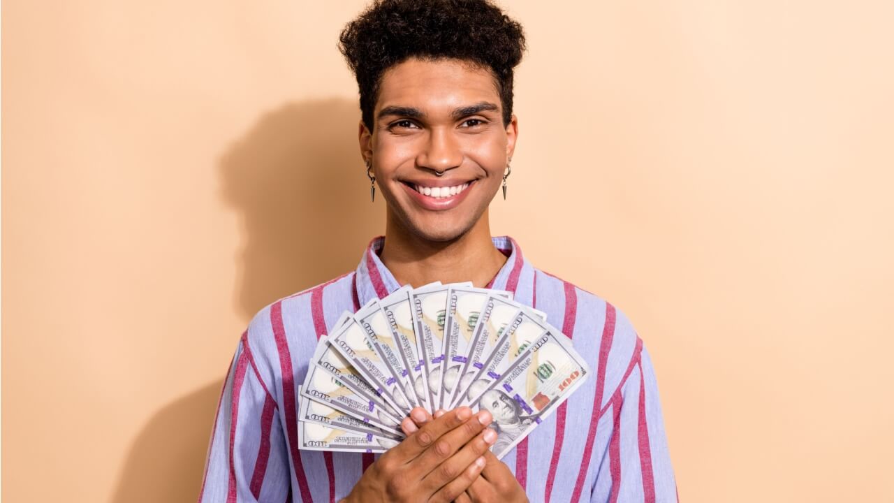 Retrato fotográfico de um homem segurando notas de dinheiro, usando uma roupa formal listrada e moderna, isolado em um fundo de cor bege.