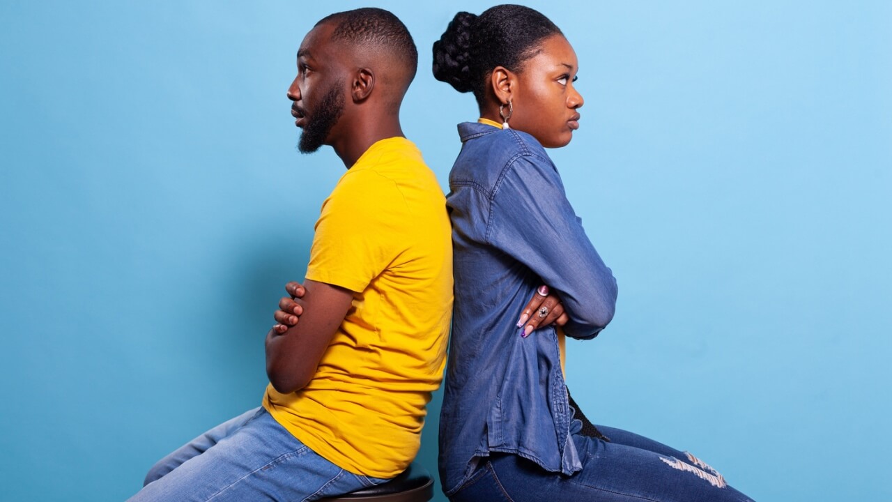 Pessoas irritadas sentadas de costas uma para a outra, com os braços cruzados em um estúdio. Conceito de problemas de relacionamento e brigas; casal chateado.