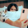 mulher deitada na cama segurando um celular