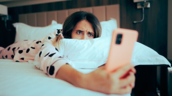 mulher deitada na cama segurando um celular