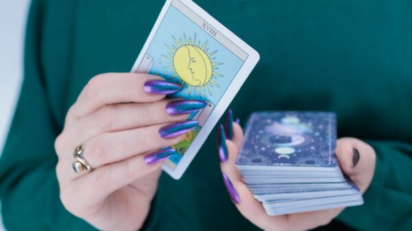 mulher com unhas pintadas de roxo segurando cartas de baralho