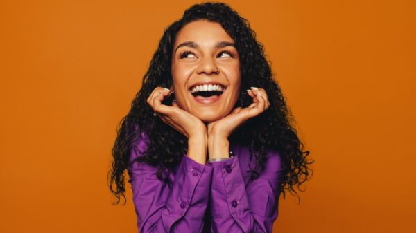 mulher negra com expressão facial de felicidade em fundo amarelo