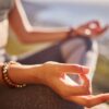 fotografia focada nas mãos de uma mulher meditando ao ar livre