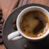 grãos de café e uma xícara branca de café