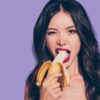 mulher com uma banana na boca em fundo roxo