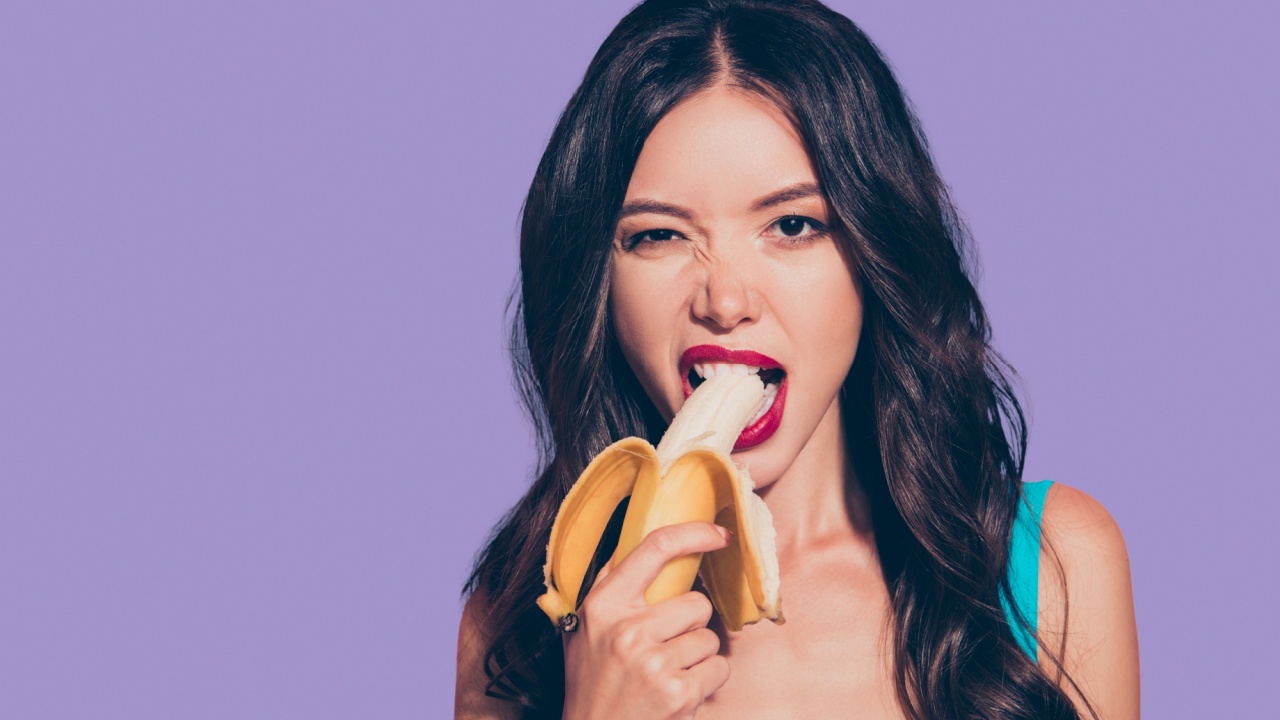 mulher com uma banana na boca em fundo roxo