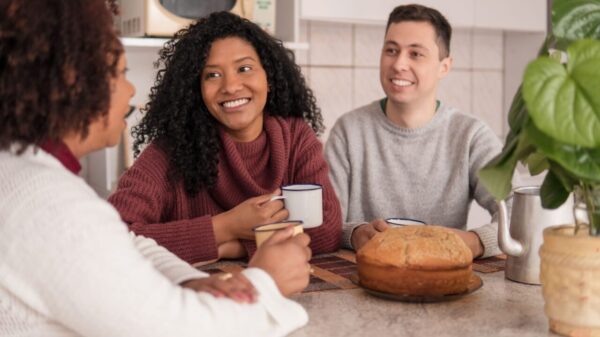 casal sentando na mesa da cozinha com a sogra sentada na ponta da mesa e todos rindo