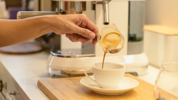 pessoa colocando café em uma xícara branca