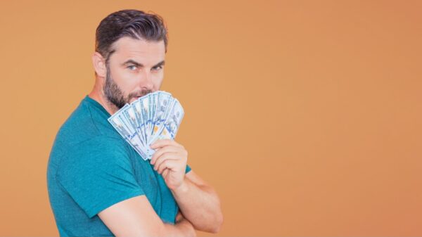 Homem segurando notas de dinheiro, isolado sobre um estúdio de fundo bege. Dinheiro em notas de dólar. Conceito de finanças.