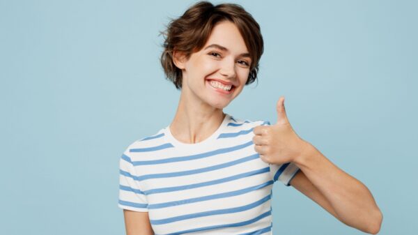 mulher fazendo sinal de positivo e sorrindo em fundo azul