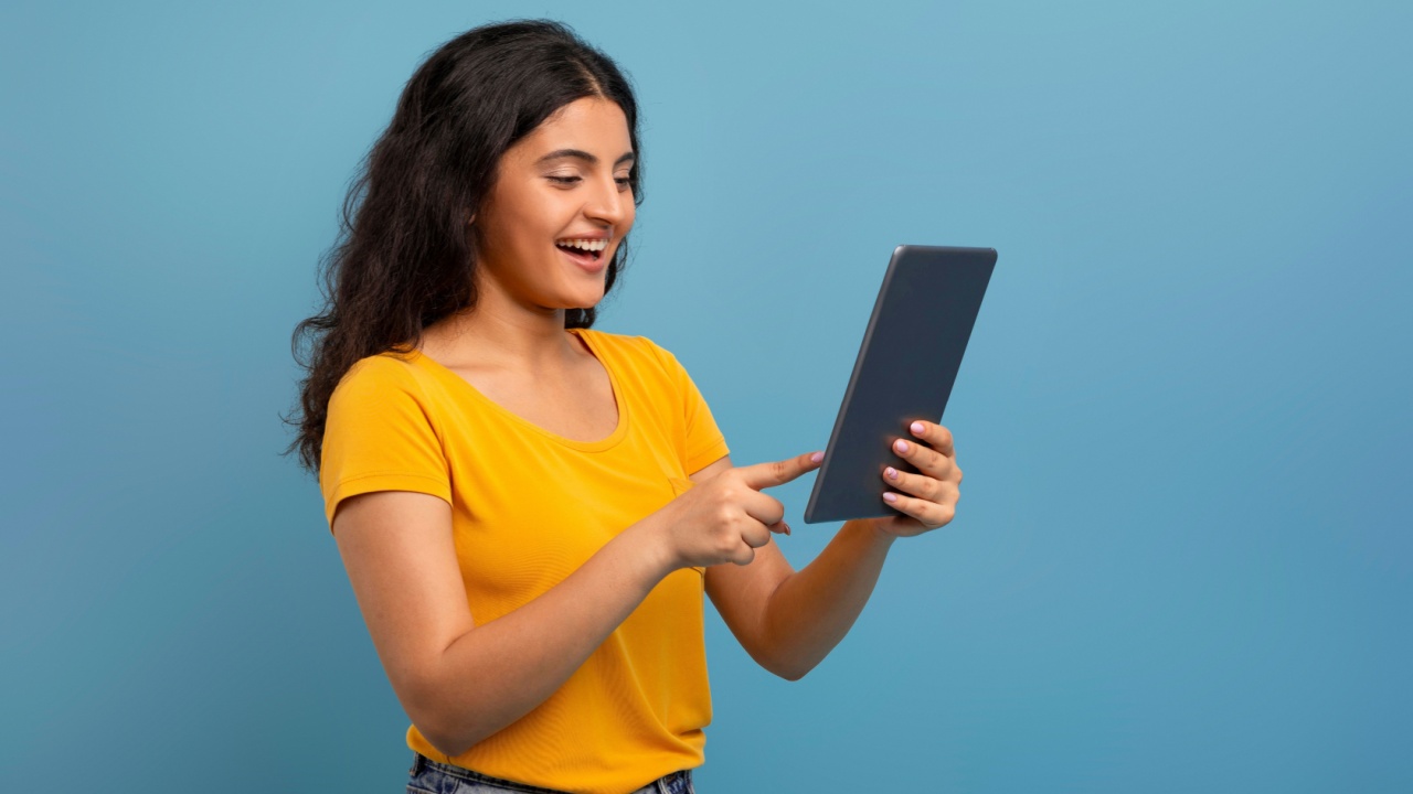 mulher segurando um tablet e sorrindo em fundo azul