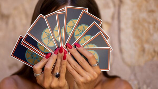 mulher segurando um baralho de cartas tampando o rosto