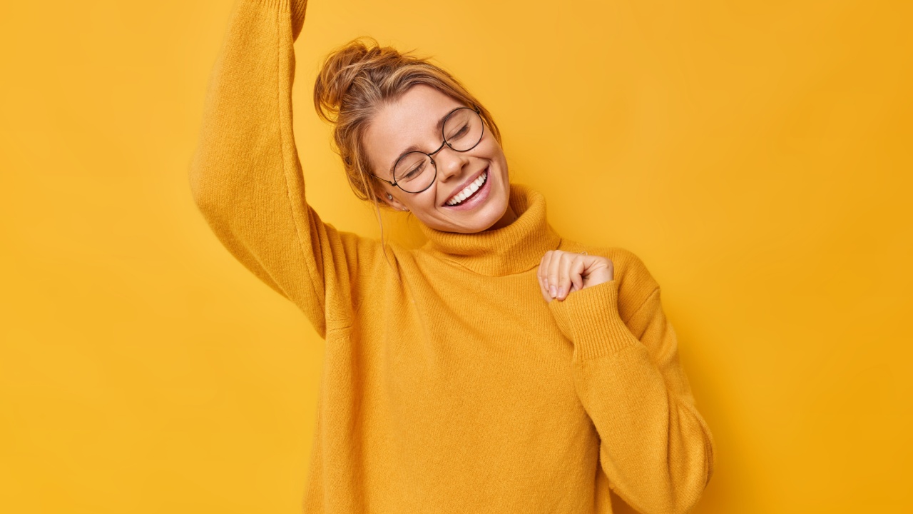 mulher com expressão facial feliz vestindo roupa amarela em fundo amarelo