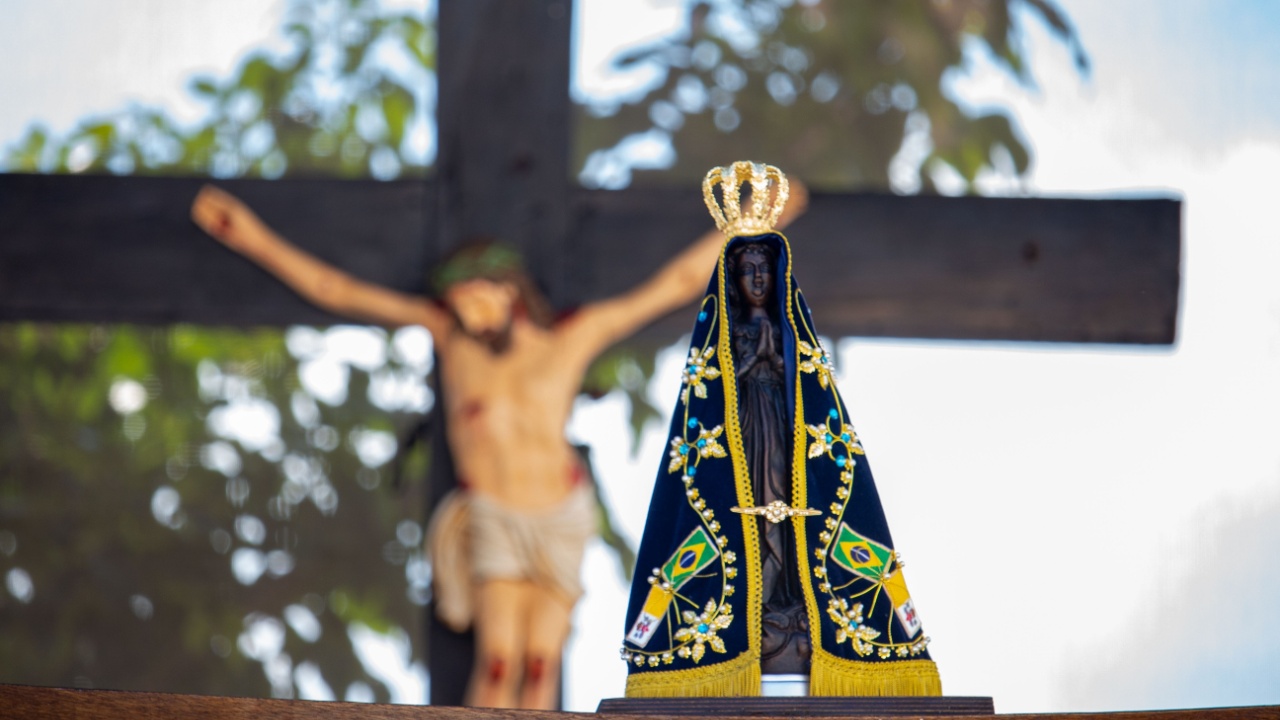 imagem de nossa senhora aparecida em primeiro plano e jesus cristo crucificado em segundo plano