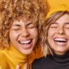 duas mulheres com grande sorriso em fundo amarelo