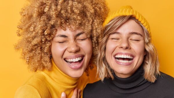 duas mulheres com grande sorriso em fundo amarelo