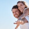 Céu azul e casal de mulher e homem feliz junto ao ar livre.