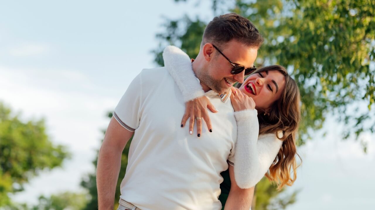 casal feliz ao ar livre e ambos vestindo branco