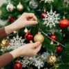 mãos feminina montando uma árvore de natal em fundo branco