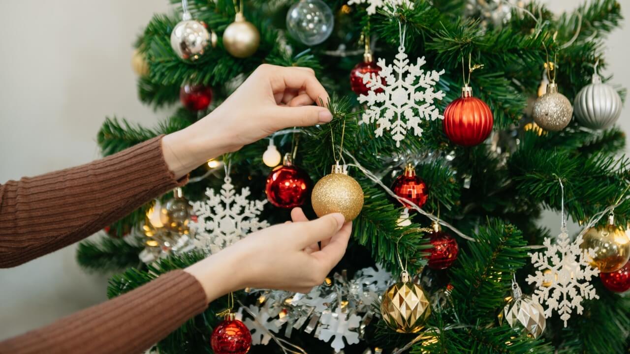 mãos feminina montando uma árvore de natal em fundo branco