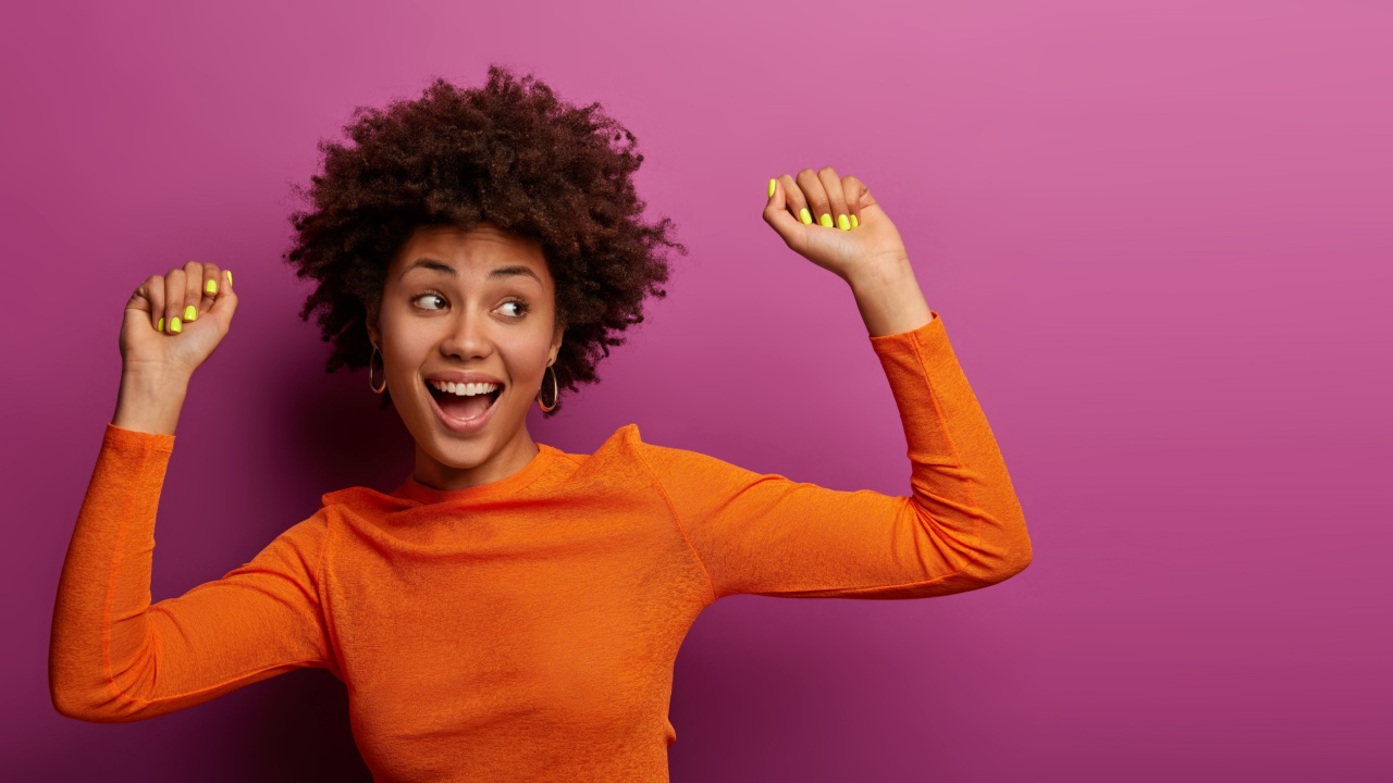 mulher negra usando roupa laranja e comemorando em fundo magenta