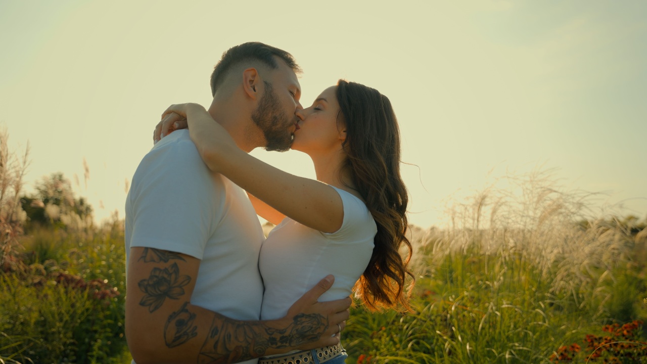 casal se beijando em um campo aberto no pôr do sol