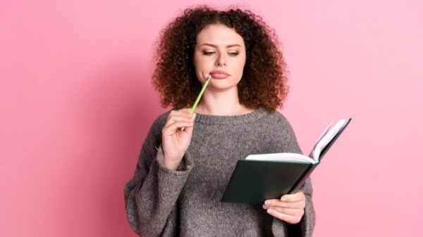 mulher com caderno na mão em fundo rosa