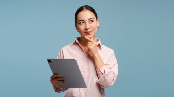 mulher de traços asiáticos segurando um tablet em fundo azul