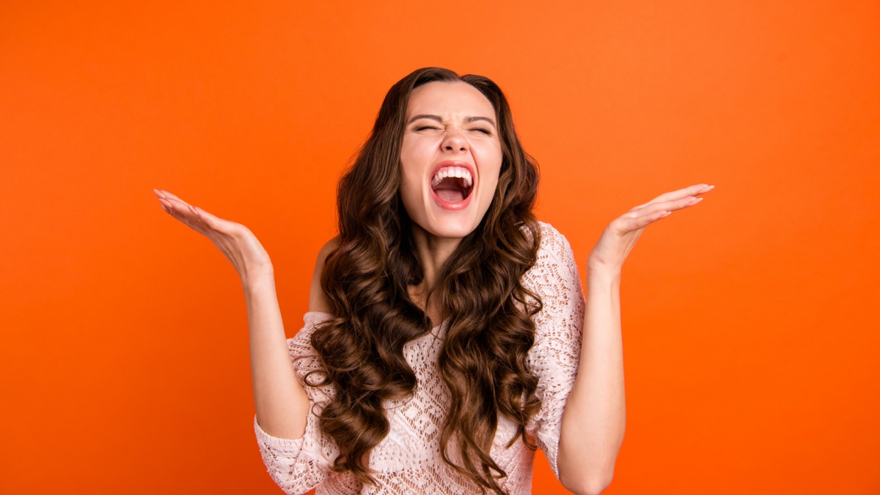 mulher feliz com os braços levantados na altura do ombro em fundo laranja