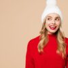 mulher com gorro de natal e blusa de lã vermelha em fundo salmão