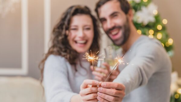 casal ao fundo e desfocado segurando velas de faísca em primeiro plano