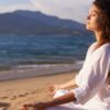 mulher sentada meditando na praia