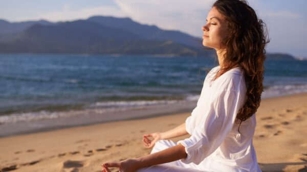 mulher sentada meditando na praia