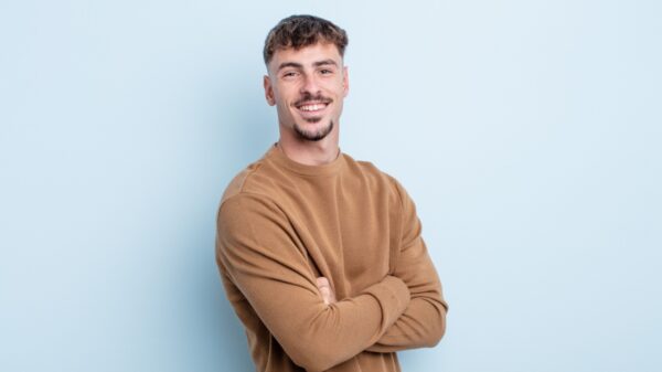 homem sorrindo com braços cruzados em fundo claro