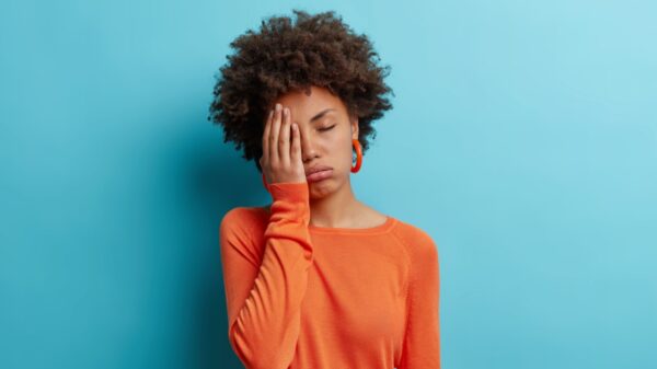 mulher com cara de chateação e a mão no rosto em fundo azul