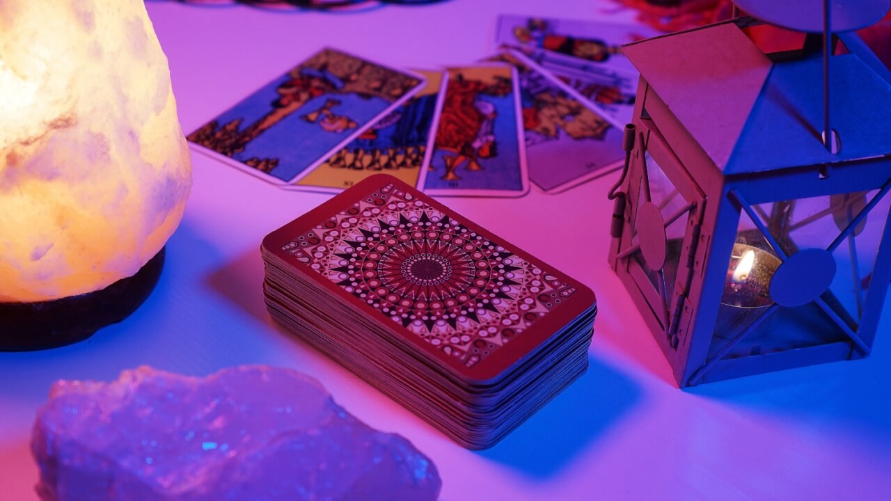 imagem de uma mesa com cartas de tarot iluminadas por luz roxa