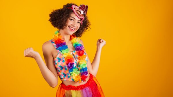 mulher com roupas de carnaval sorrindo em fundo amarelo