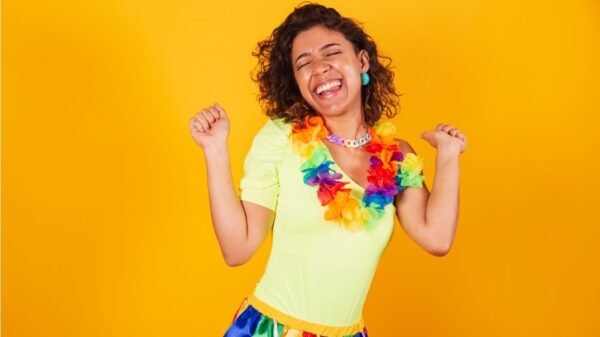 Mulher com roupas de carnaval, dançando com colar de flores.